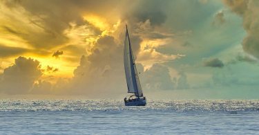 Ship sailing toward sunrise and storm