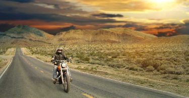 Man on motorcycle riding through the desert at sunset