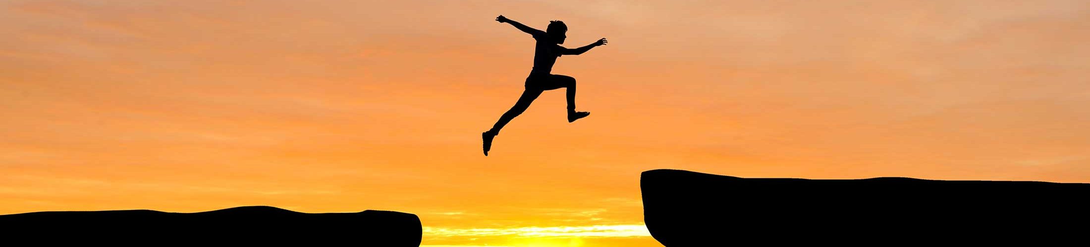 Person jumping over a gap at sunrise