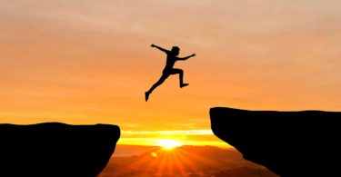 Person jumping over a gap at sunrise