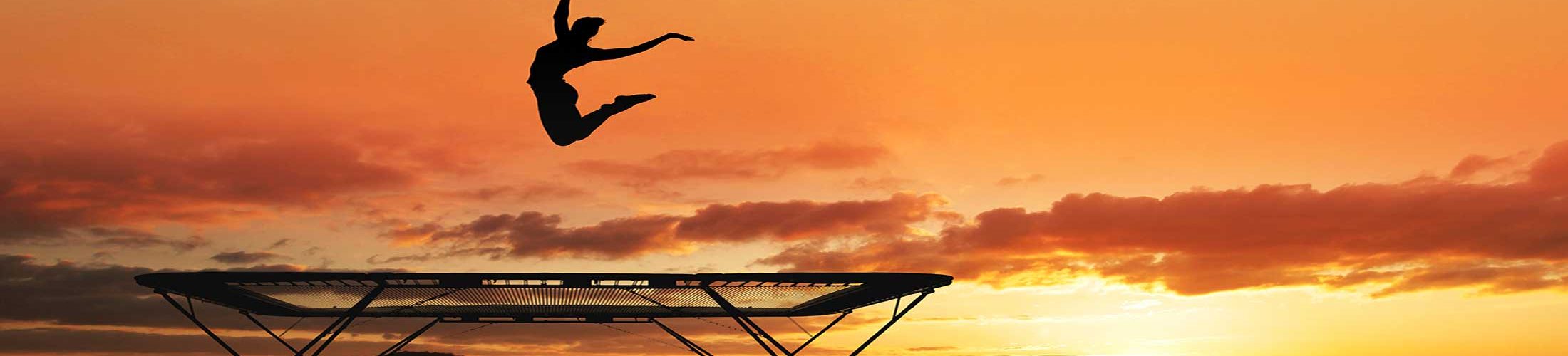 Woman jumping trampoline sunset