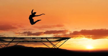 Woman jumping trampoline sunset