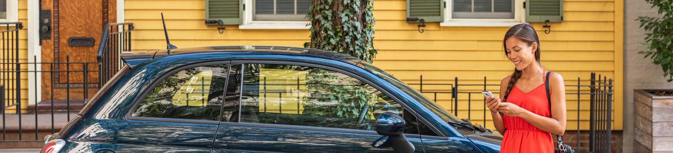 Woman reading phone outside blue fiat