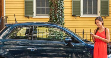 Woman reading phone outside blue fiat