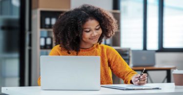 Woman sitting desk writing paper